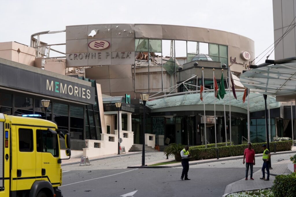 Security and civil defence workers stand outside the damaged Crown Plaza hotel, following an Iranian military strike, in Manama on March 1, 2026.